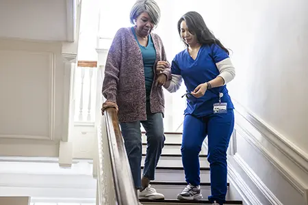 woman helping another woman down the stairs