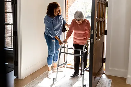 woman helping woman in house with a walker